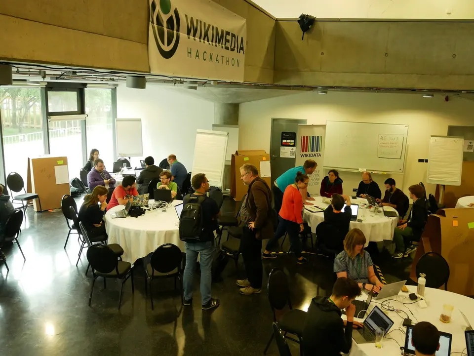 Personas trabajando en mesas con portátiles en un espacio abierto